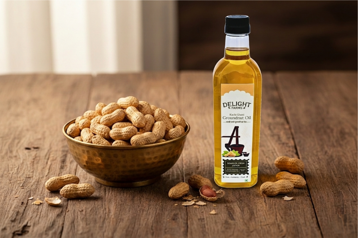 Rustic wooden table with brass bowl of shelled groundnuts and cold pressed groundnut oil bottle