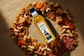  Groundnut oil bottle with dry fruits, jaggery, and fresh peanuts on burlap cloth 